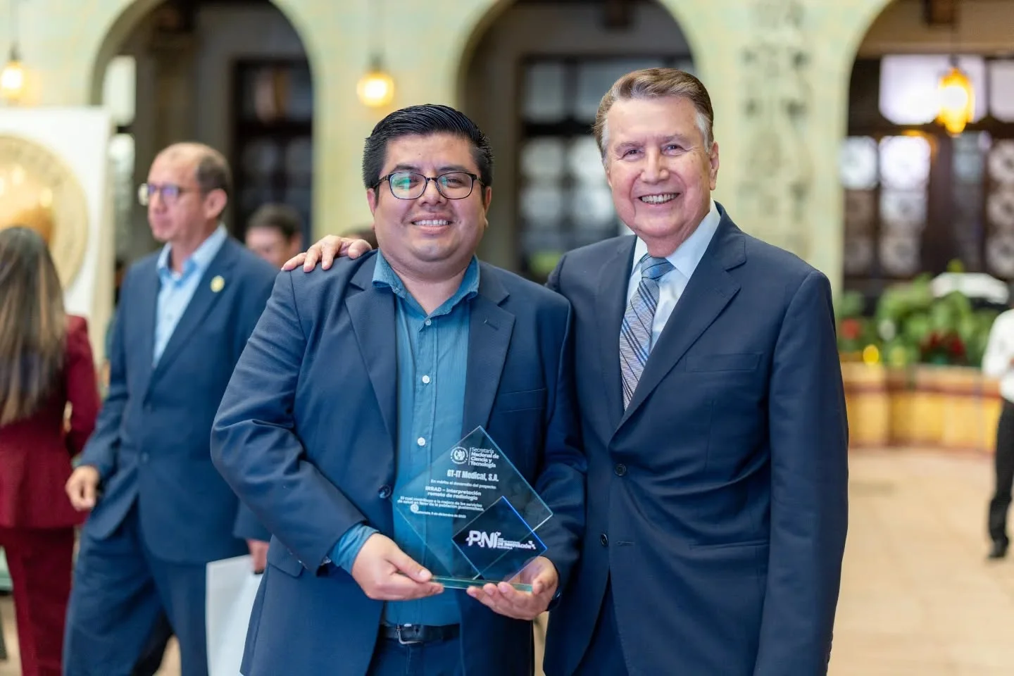 Entrega del Premio Nacional de Innovación 2025 de SENACYT Guatemala a
                      GT-IT Medical. Dos personas sostienen el galardón de cristal.